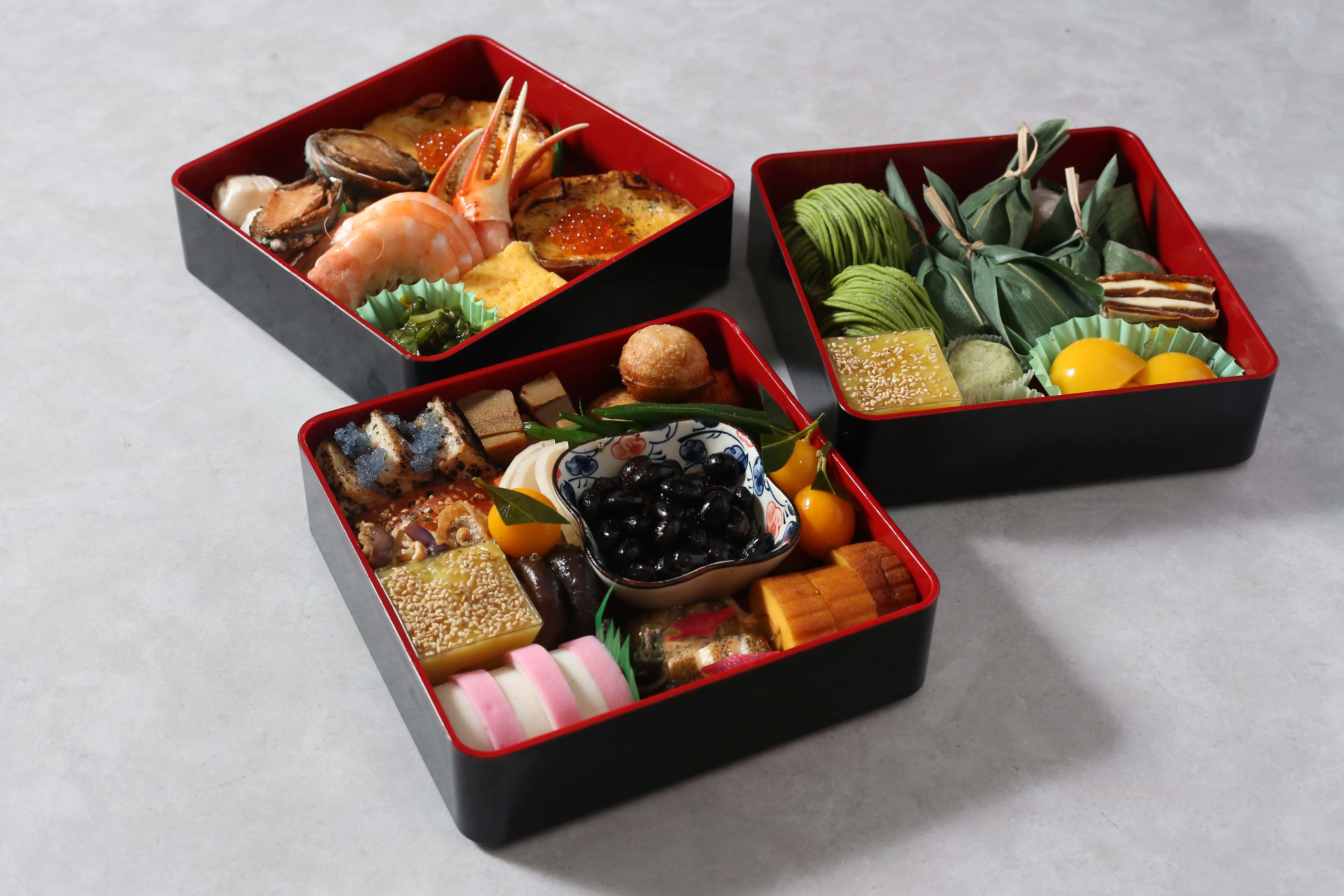 Three tiered Osechi boxes filled with traditional Japanese New Year foods.
