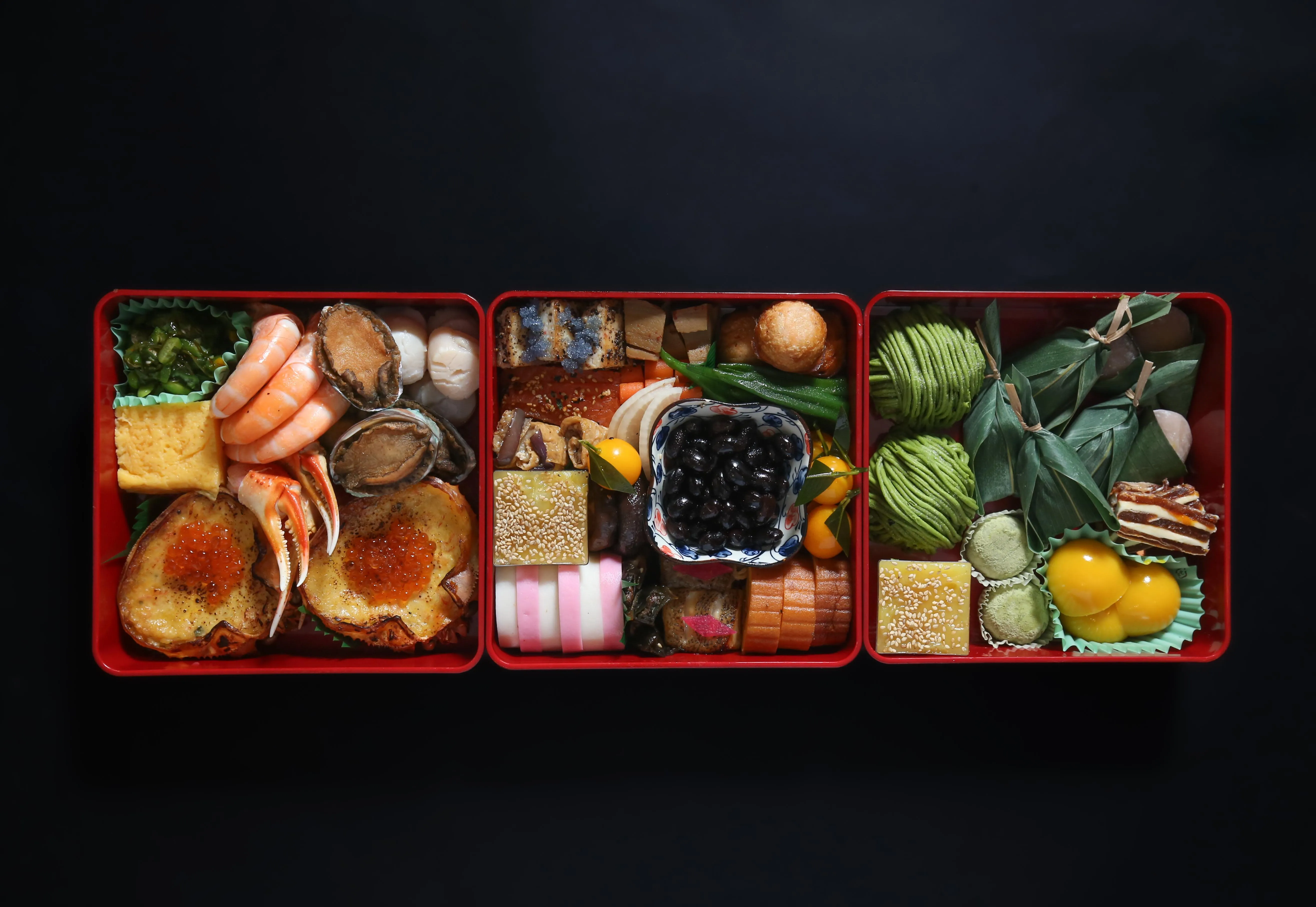 A beautifully arranged osechi ryori, a traditional Japanese New Year feast, in red lacquer boxes.